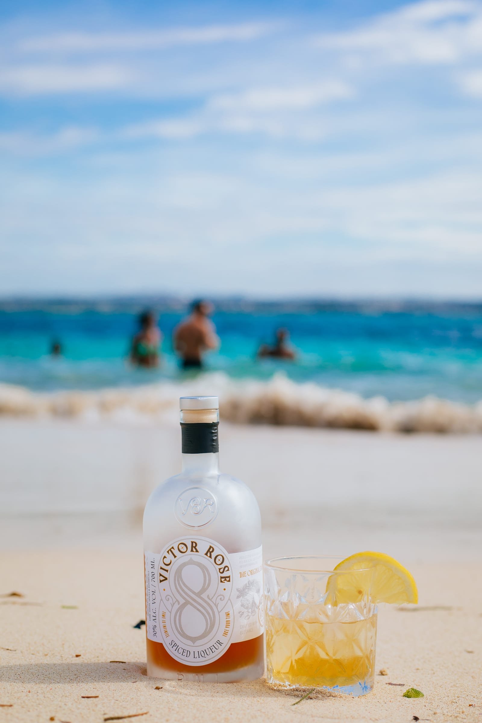 Victor Rose 8 bottle on white sand beside a turquoise Tanzanian coastline